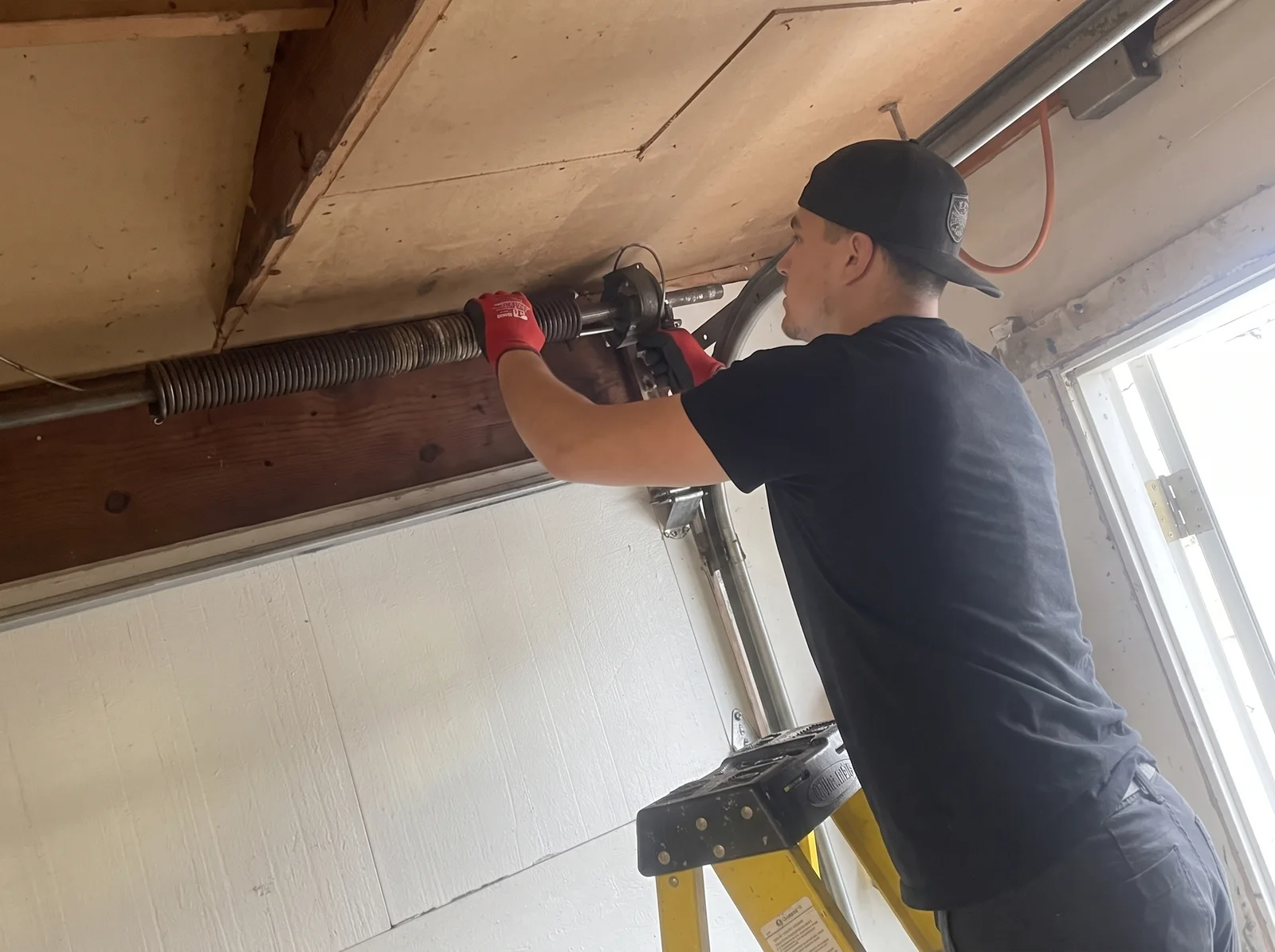 Technician working on the spring assembly above a garage door