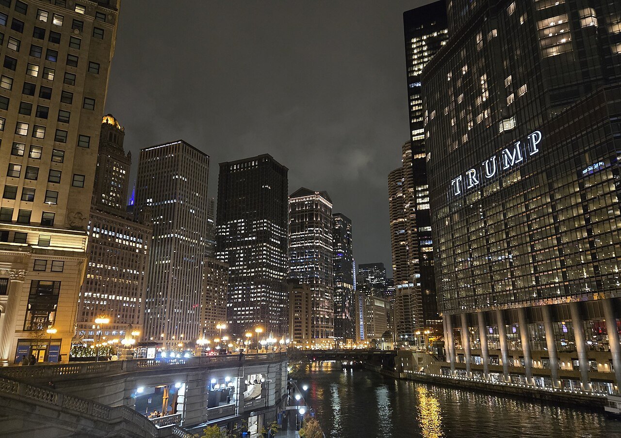 Illuminated Chicago skyscrapers reflected in the Chicago River at night.