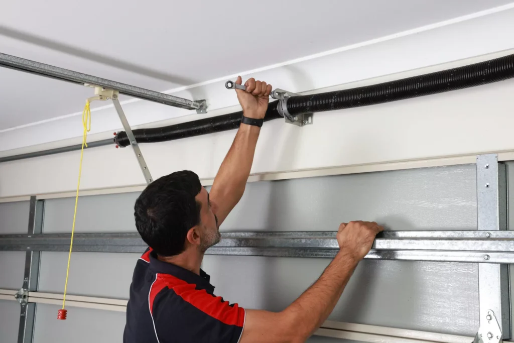 Technician adjusting a torsion spring above a sectional garage door