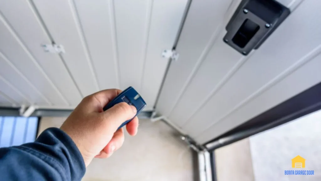 Hand holding a remote beneath a residential garage door opener