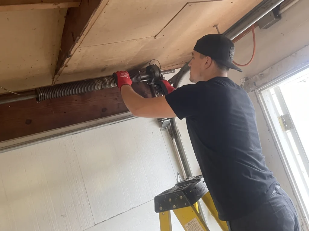 Technician servicing the spring assembly above a garage door